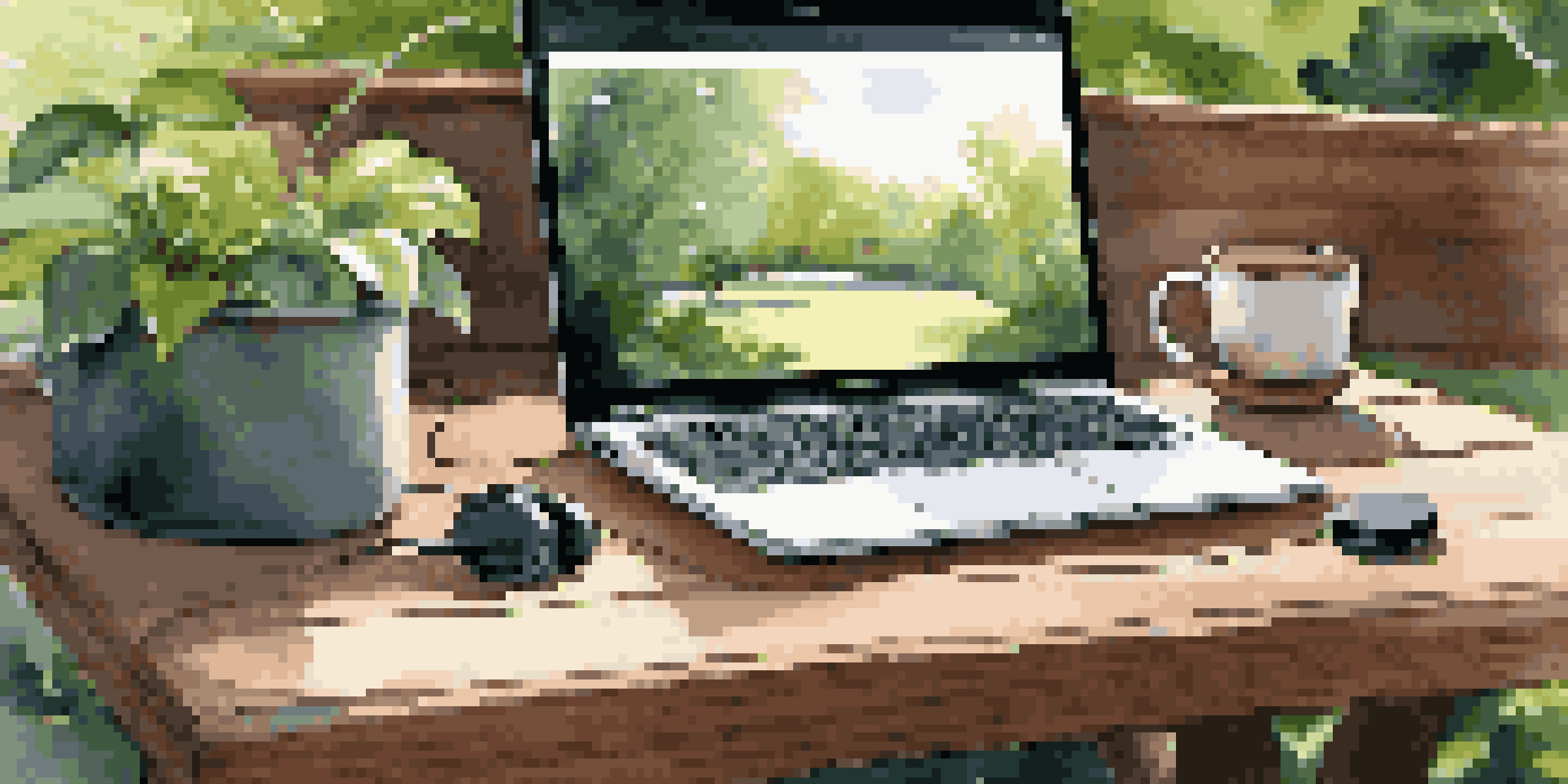 An outdoor workspace with a laptop, portable monitor, headphones, and coffee, surrounded by greenery and sunlight.