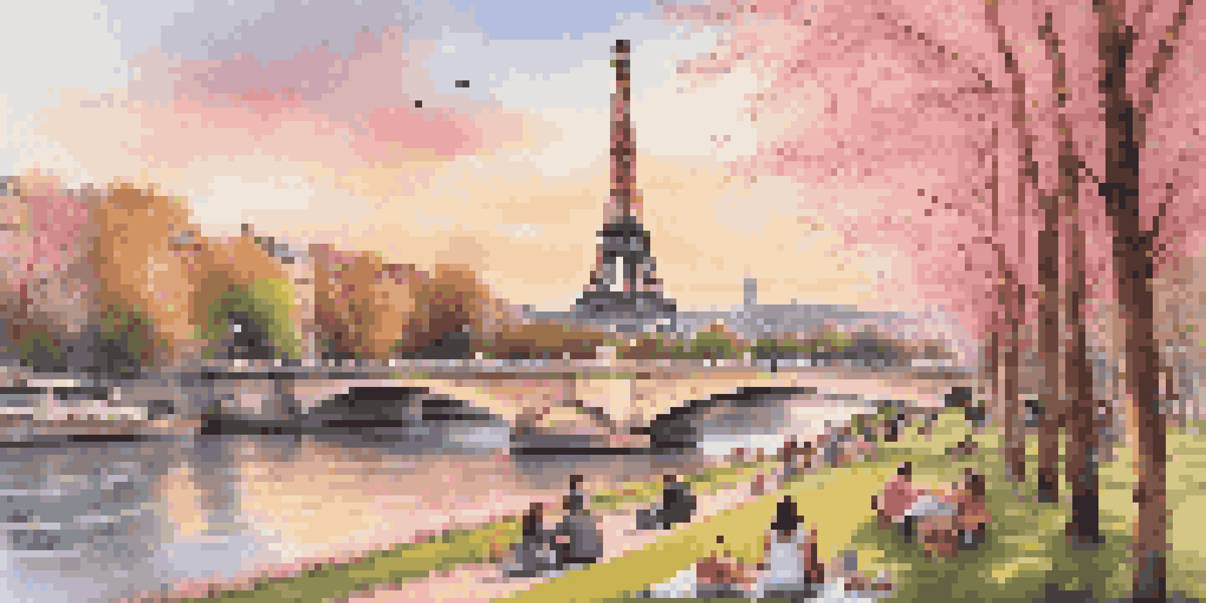 Eiffel Tower at sunset with cherry blossoms and people picnicking on the lawn.