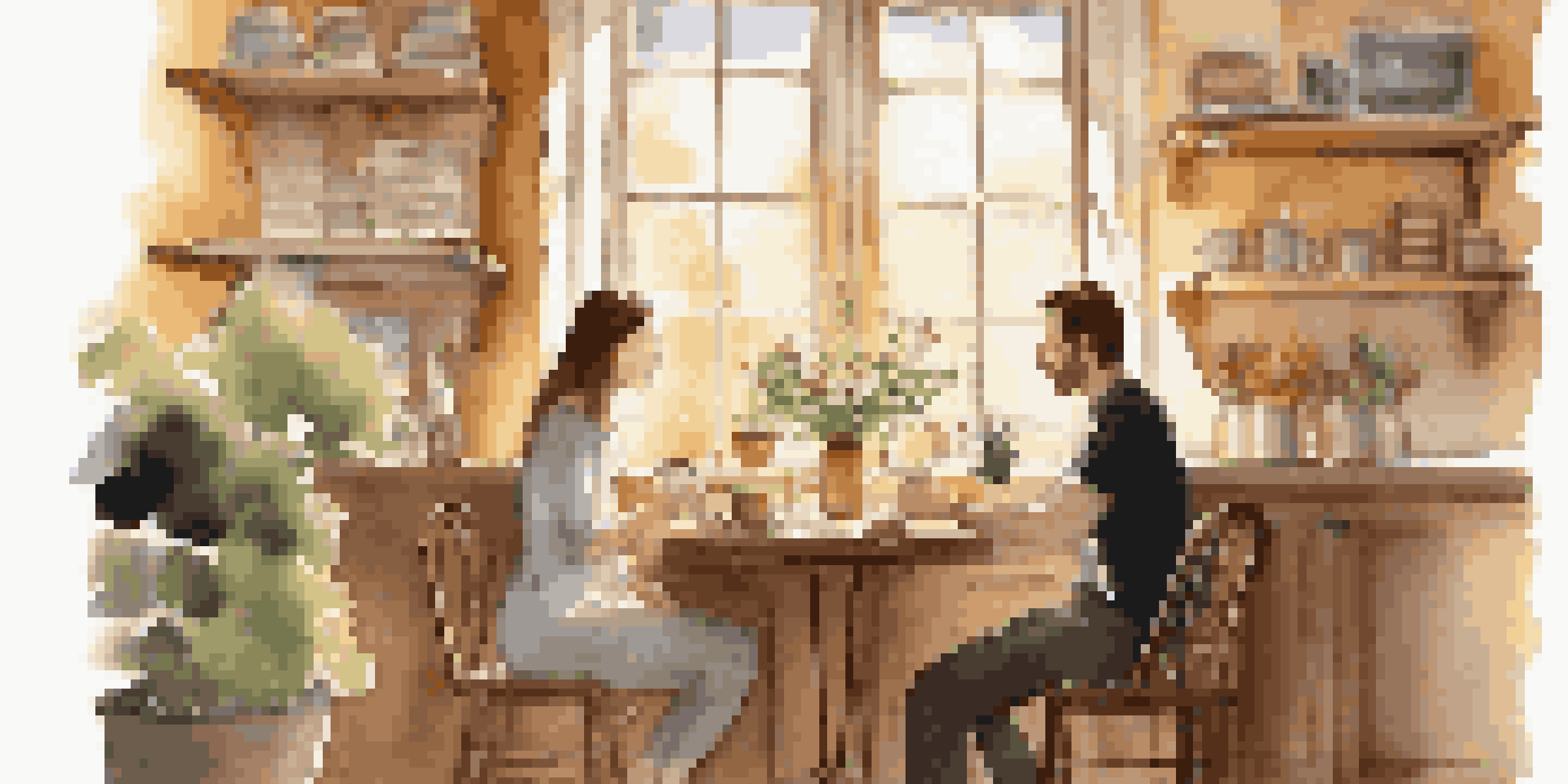 A couple enjoying coffee and conversation in a cozy café with sunlight streaming in.