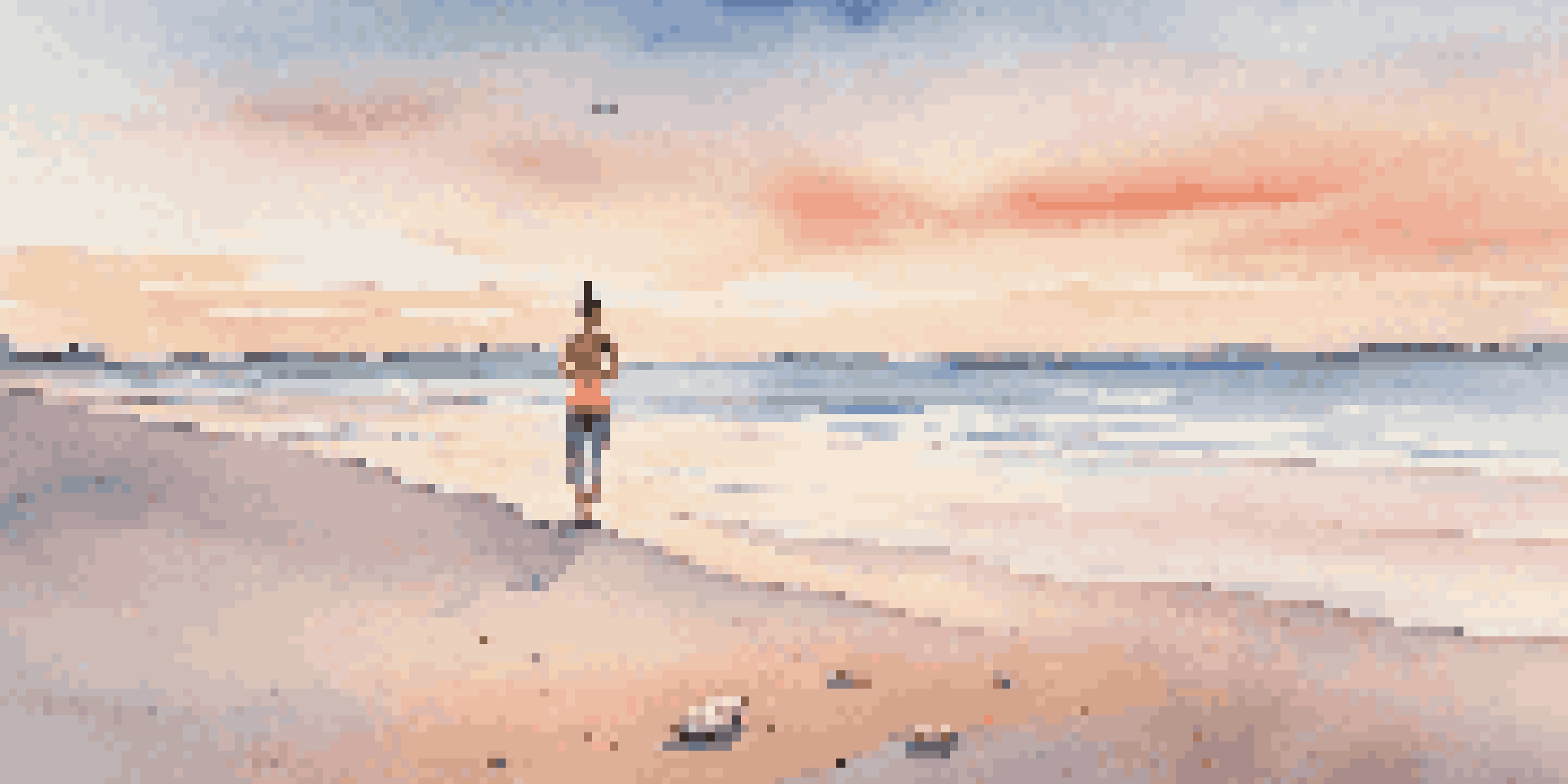 A person doing yoga on a beach at sunrise, with a colorful sky and calm water.