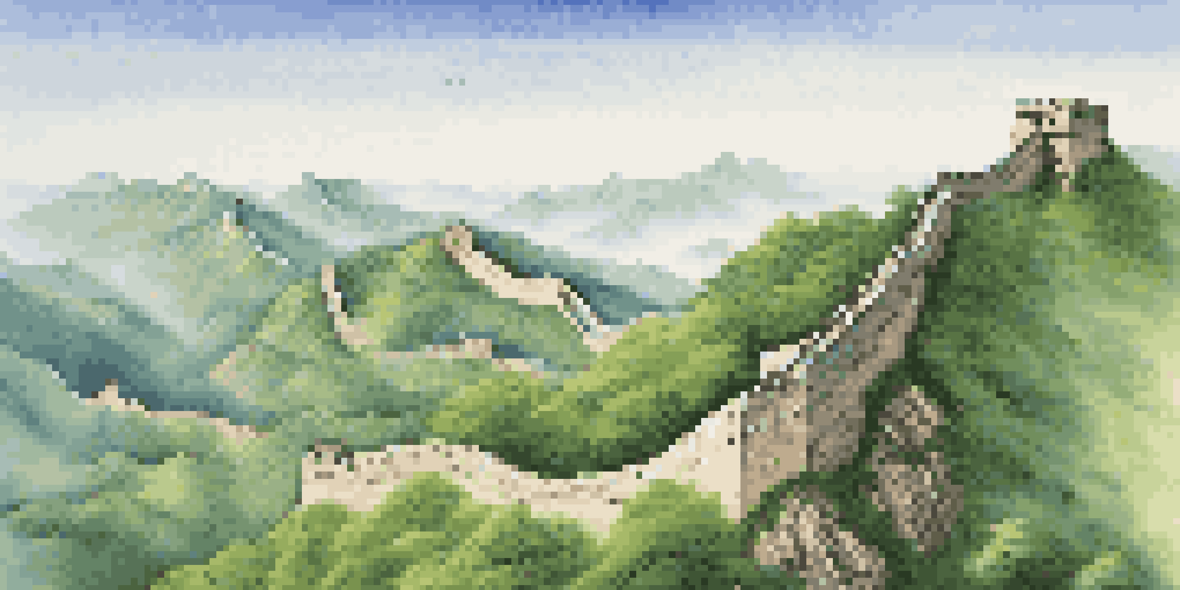 A wide-angle view of the Great Wall of China on green mountains with a clear sky.