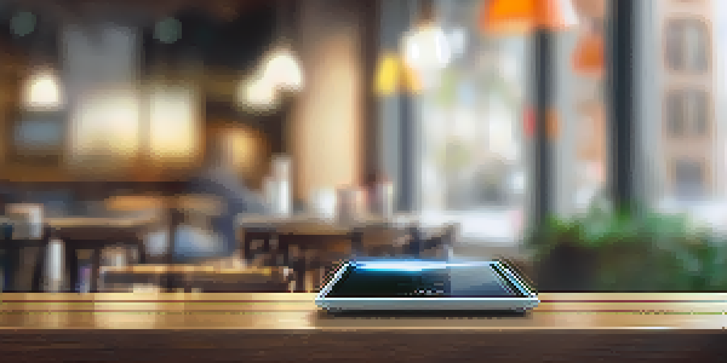 A mobile hotspot device on a wooden table with a smartphone and tablet connected to it in a cozy café setting.