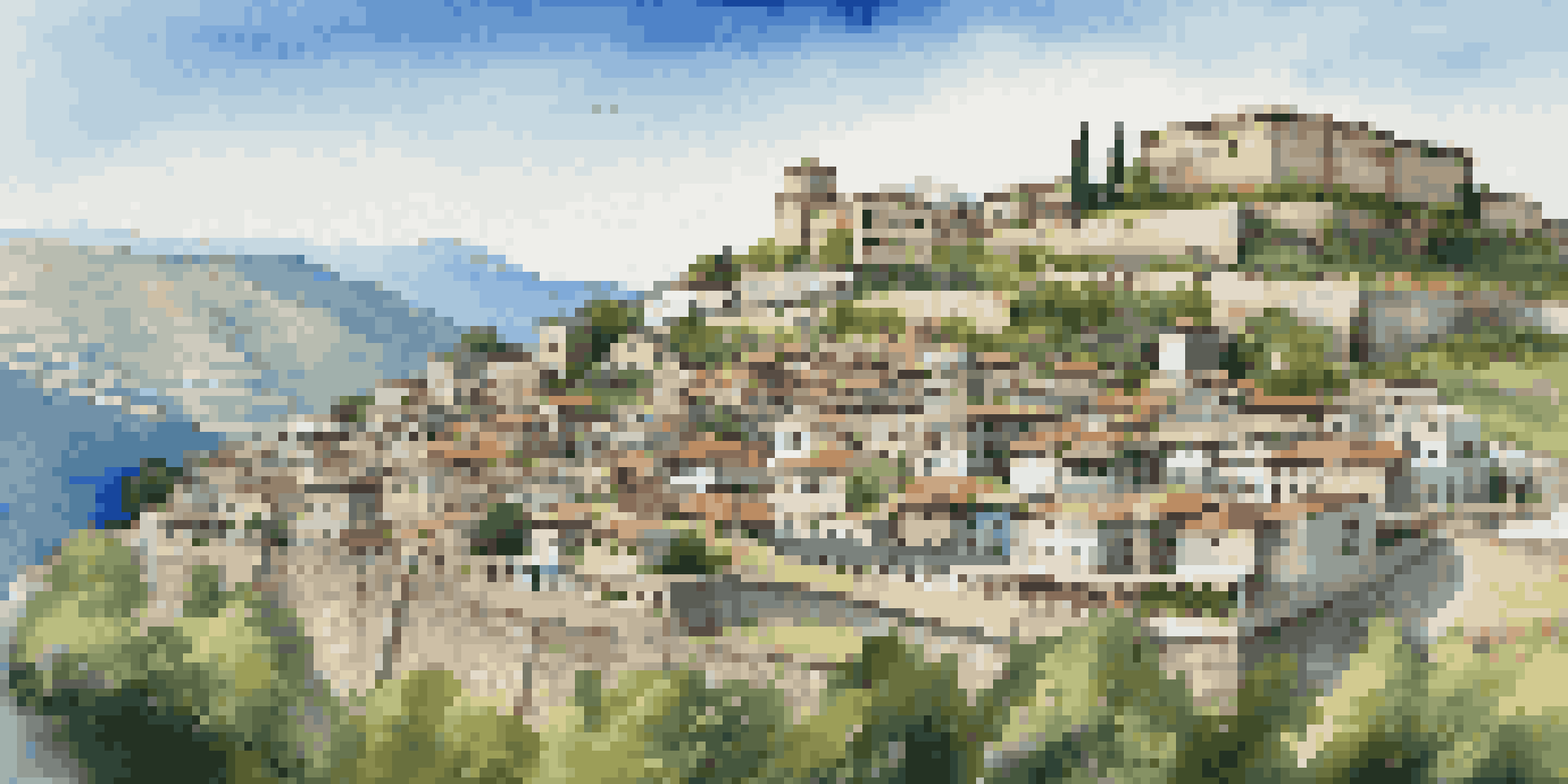 Panoramic view of Gjirokastër, Albania, featuring Ottoman architecture and a castle on a hill with green mountains in the background.