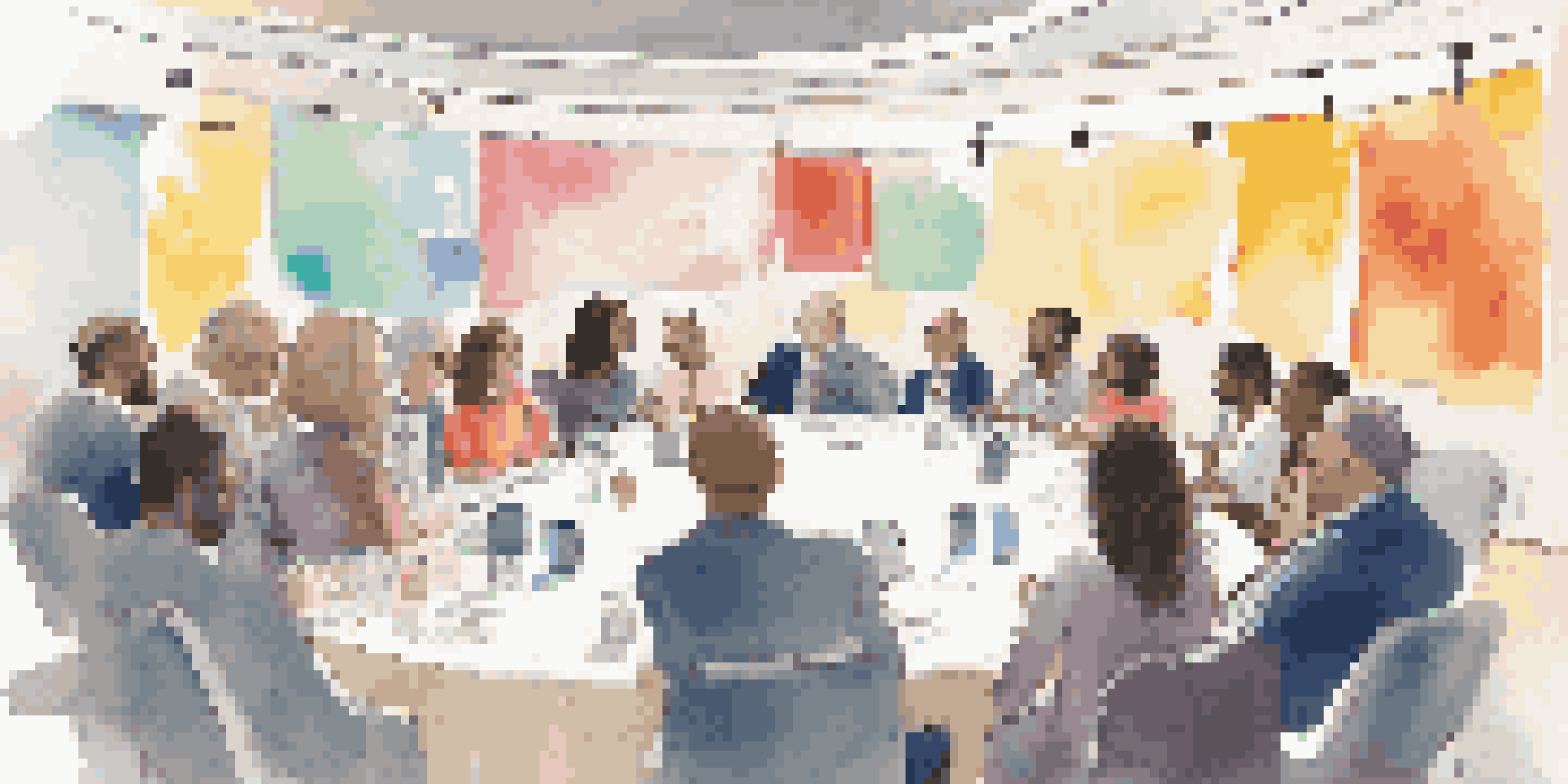 A diverse group of professionals engaging in discussion at a conference, surrounded by colorful banners and posters.