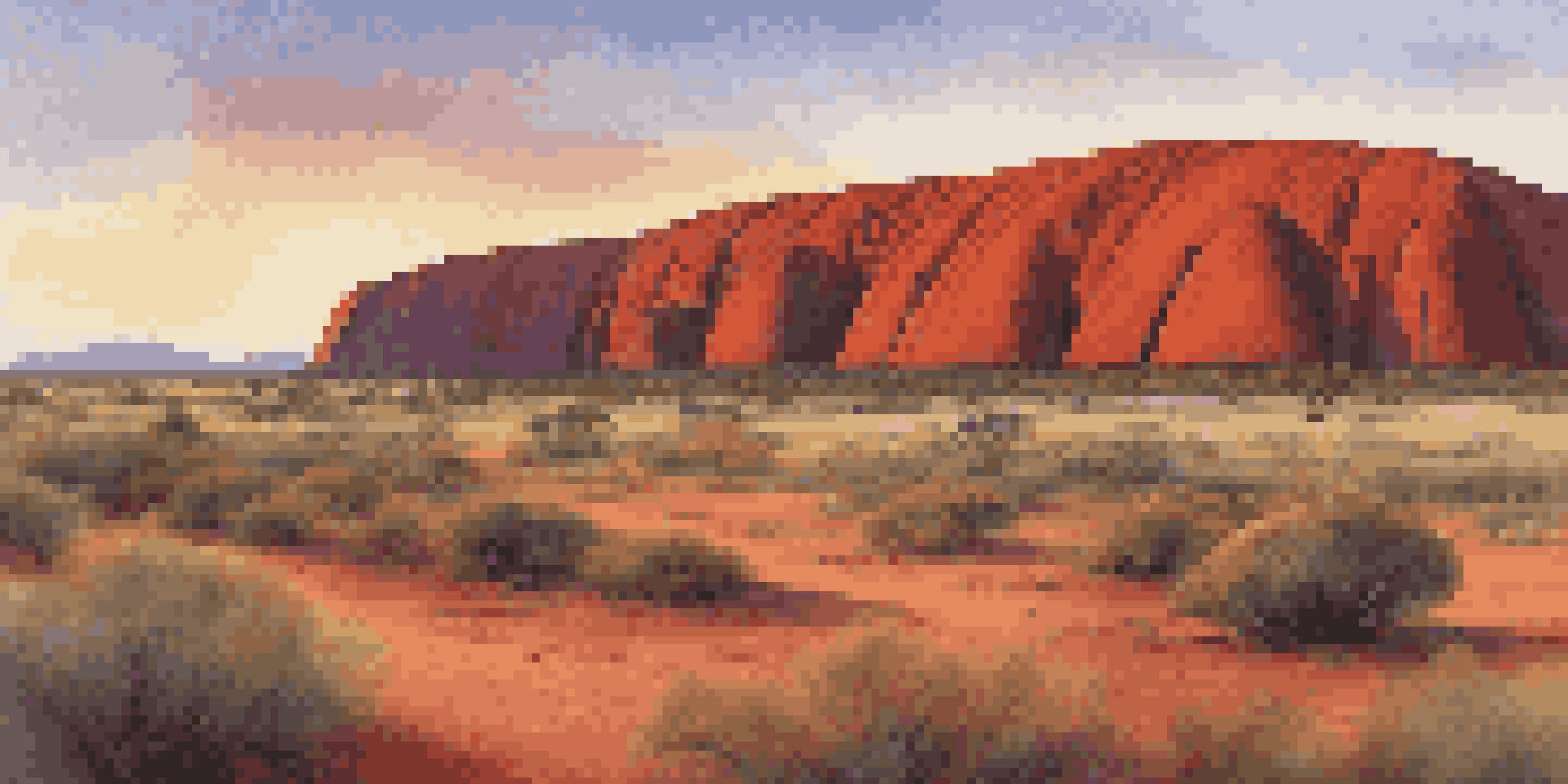 A stunning sunrise view of Uluru, showcasing the vibrant red rock against a colorful sky and desert landscape.