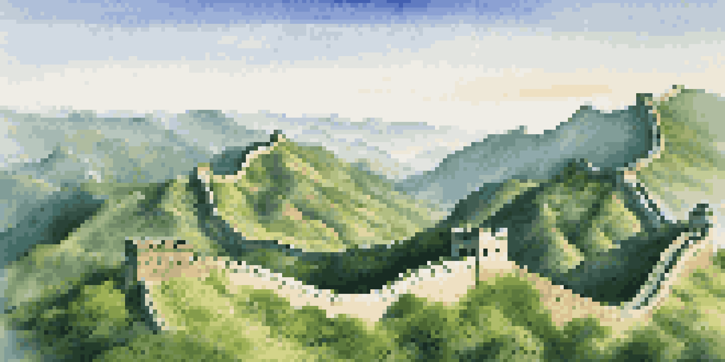 A panoramic view of the Great Wall of China surrounded by green mountains and a blue sky.