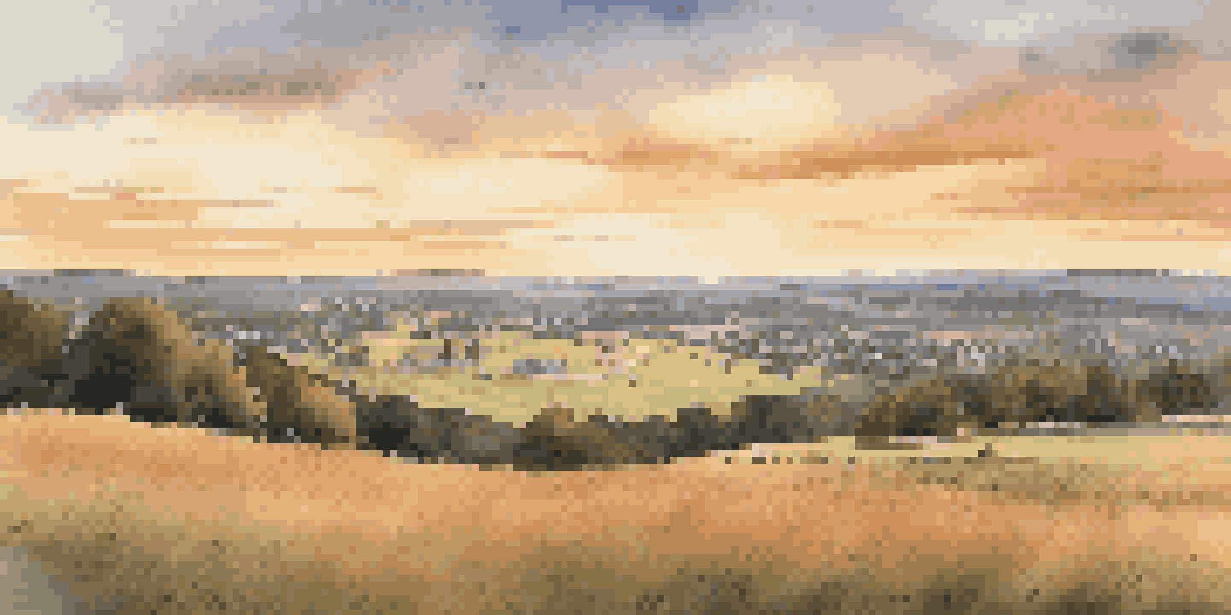 A wide view of Gettysburg National Military Park at sunset, highlighting the hills and monuments.