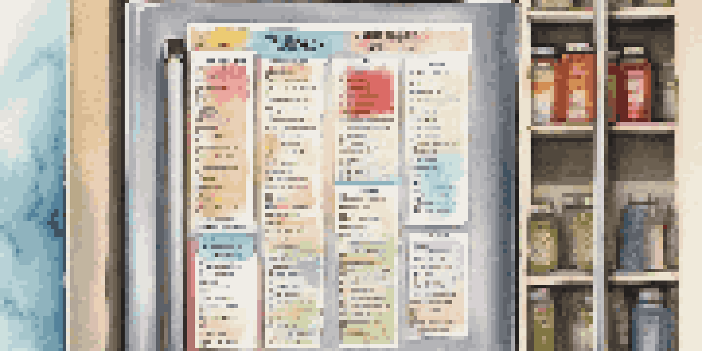 A neatly organized emergency contact list on a fridge, held by colorful magnets, with sunlight illuminating the list.