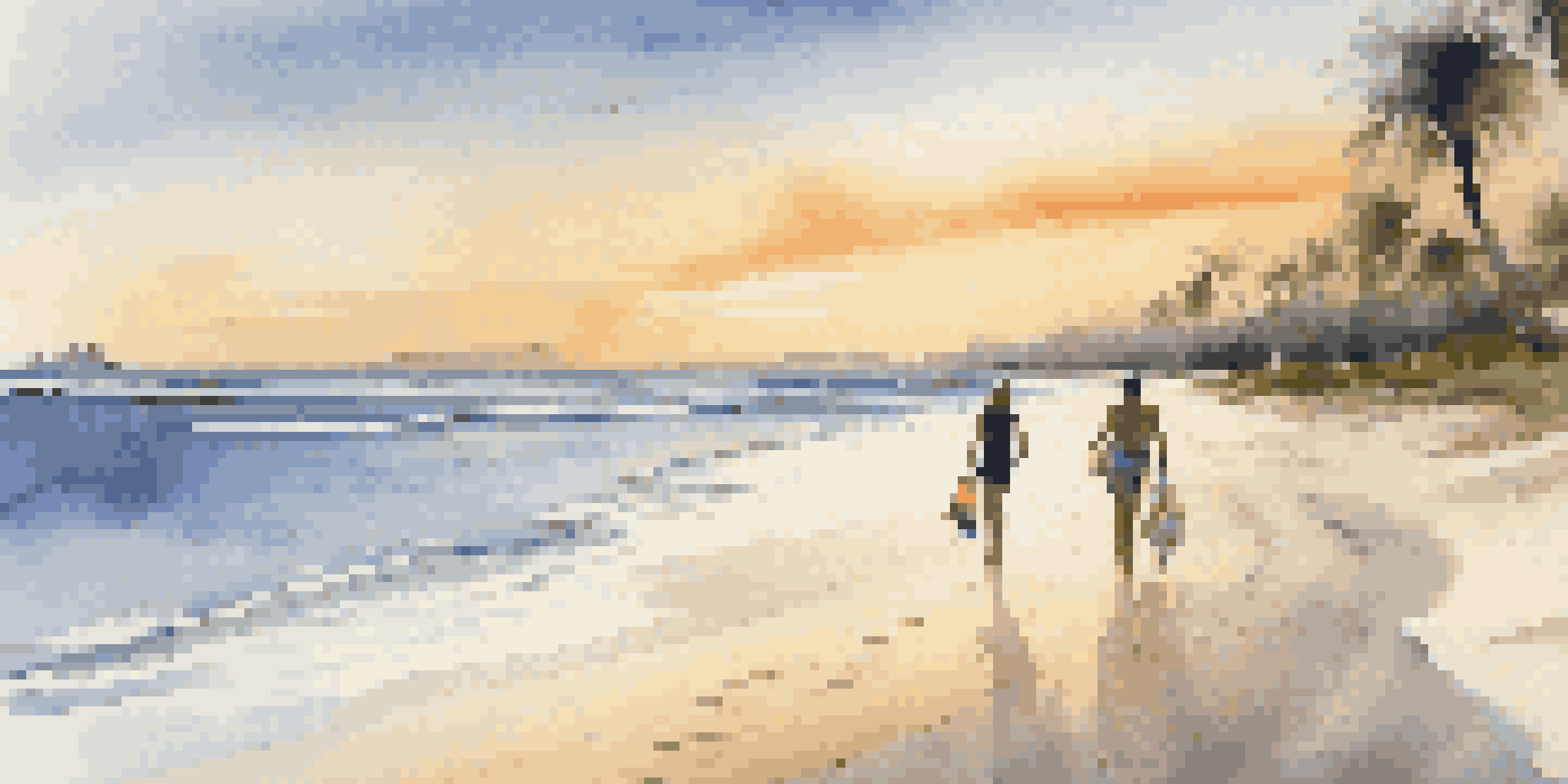 A couple walking on a beach at sunset, with palm trees and beach towels in the foreground.
