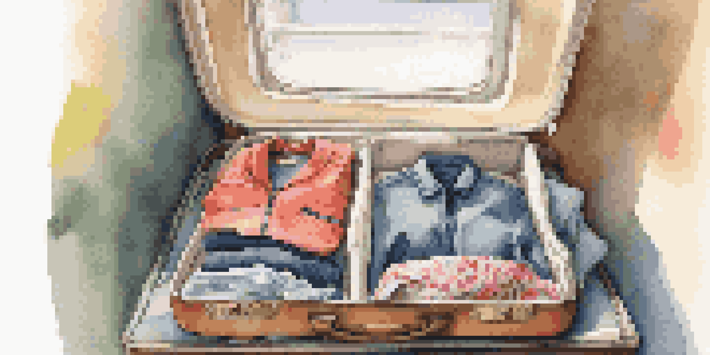 An open suitcase on a bed filled with neatly packed clothing and packing cubes in soft lighting.
