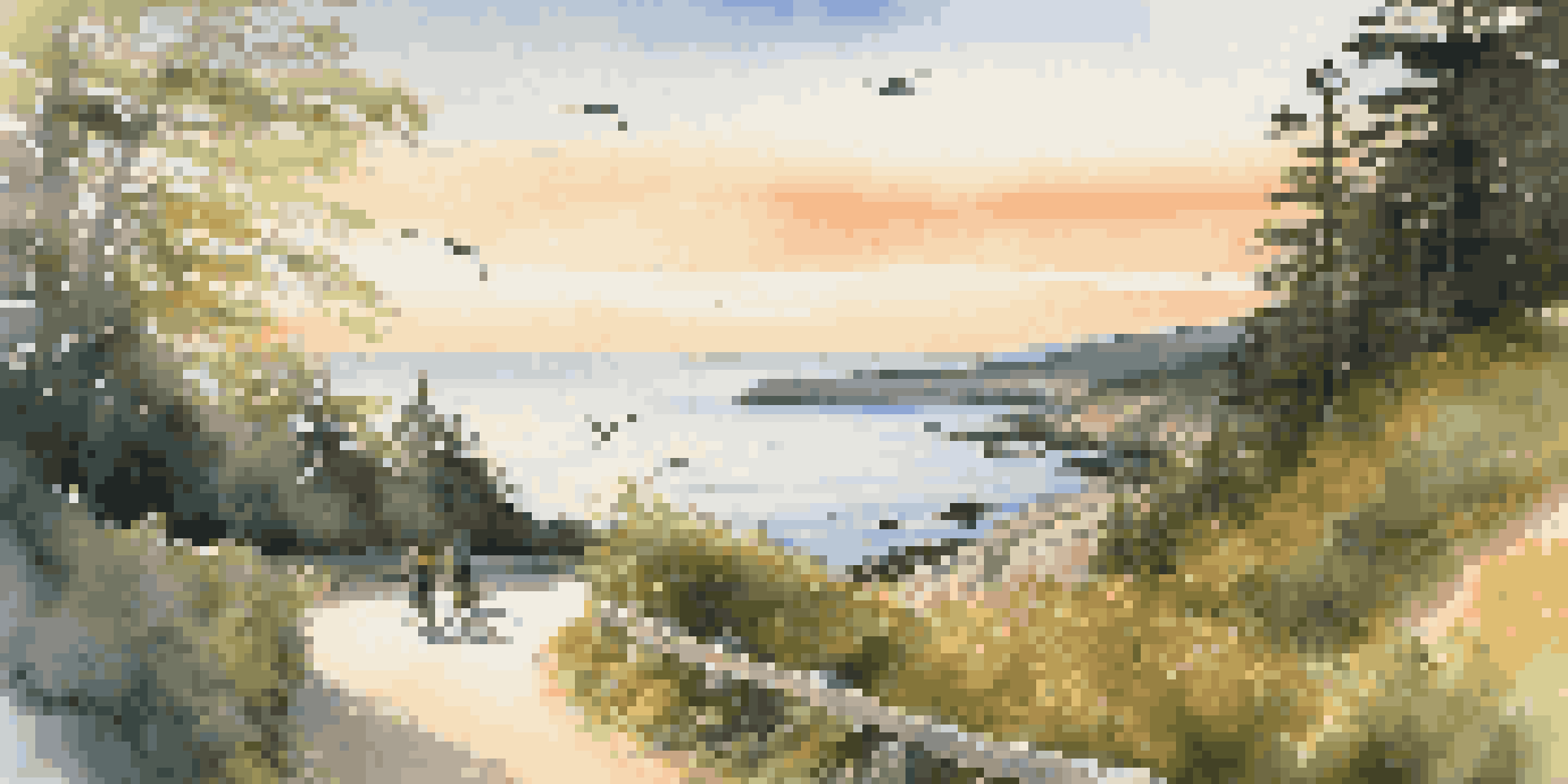 A scenic coastal bike path with cyclists and a beautiful sunset over the ocean.