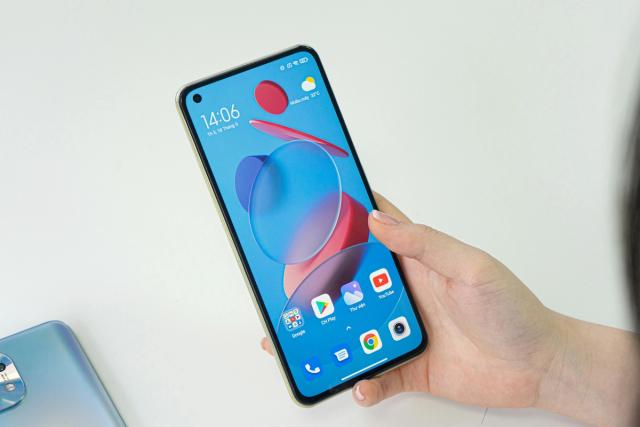 A hand holding a Xiaomi Android phone with its home screen on.