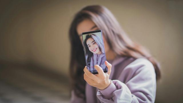 A woman taking a selfie with her phone.