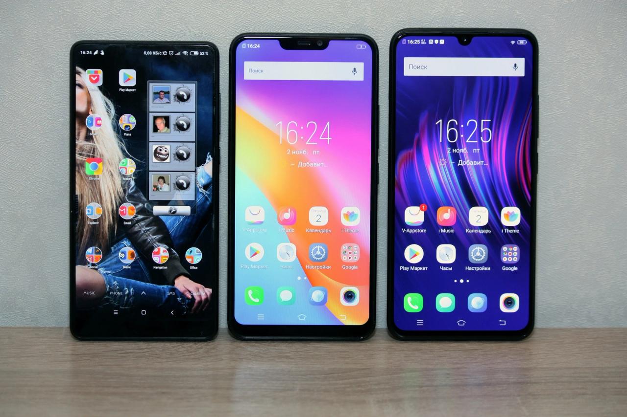 Three different smartphones standing side by side with their screens on.