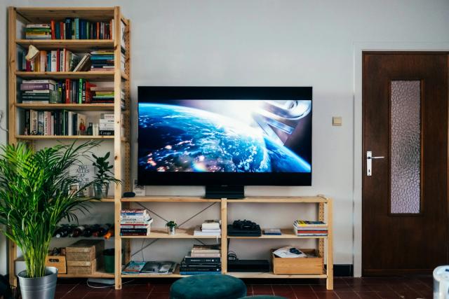A large flat-screen TV in a living room, next to wooden bookshelves.