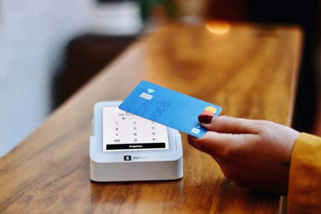A person tapping a bank card on a card payment machine.