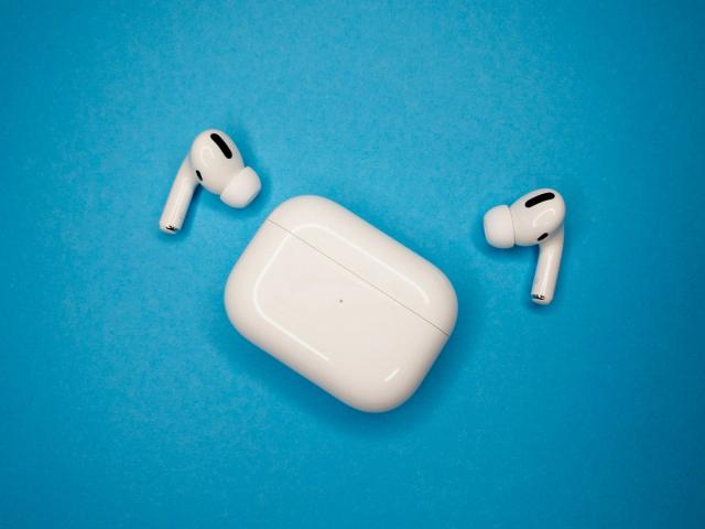 Apple AirPods Pro earbuds and their charging case on a blue background.