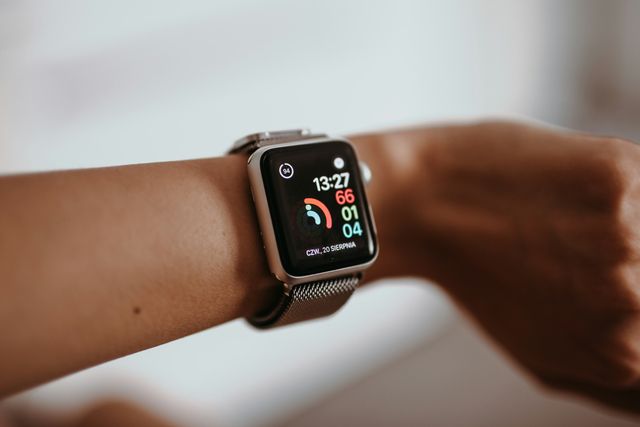 An Apple Watch with a metal mesh band on a person's wrist, showing the time and activity rings.
