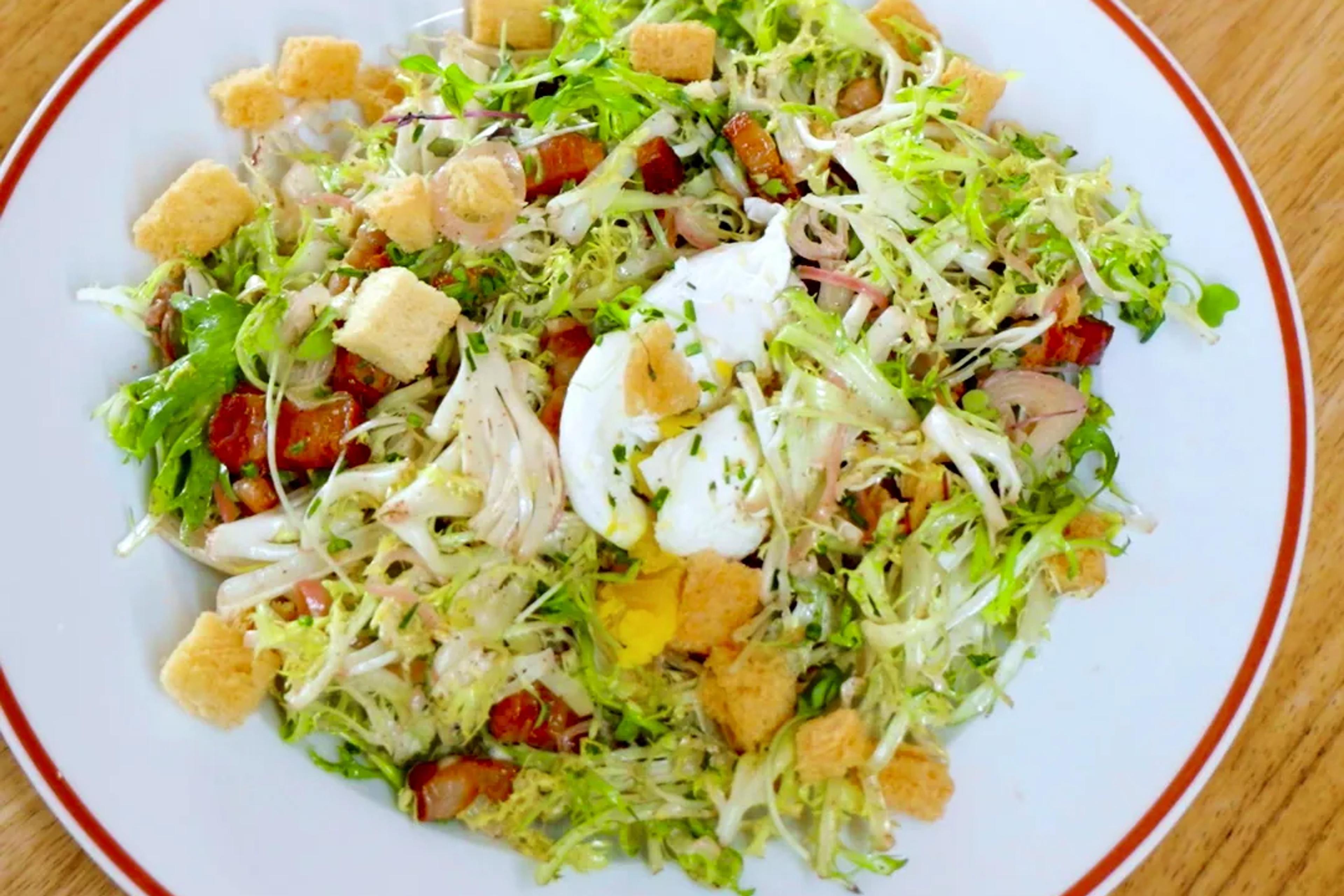 Salade Lyonnaise on an Amélie plate: frisée, bacon, croutons and a poached egg