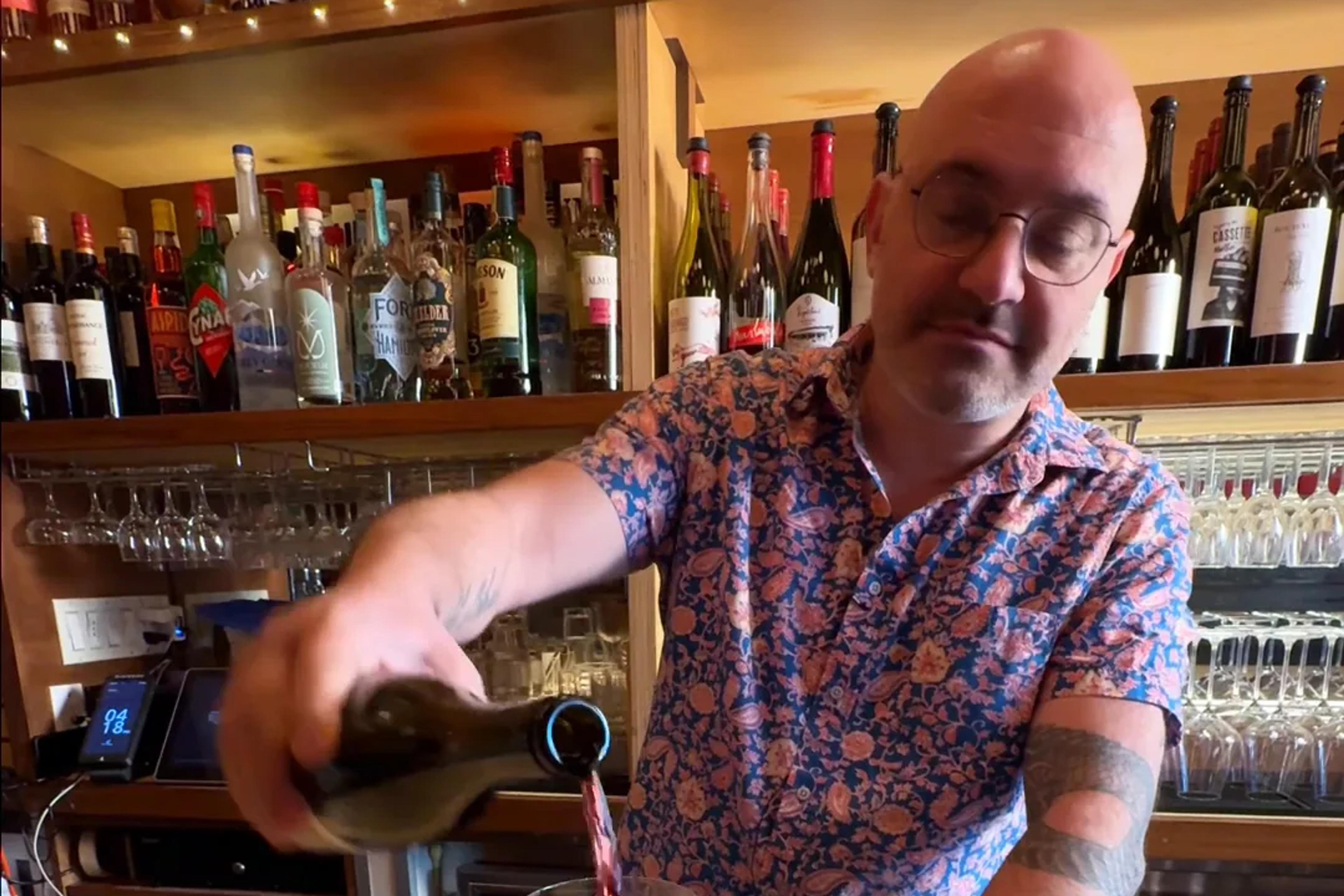A bartender pouring a glass of red wine at Amélie Upper West Side