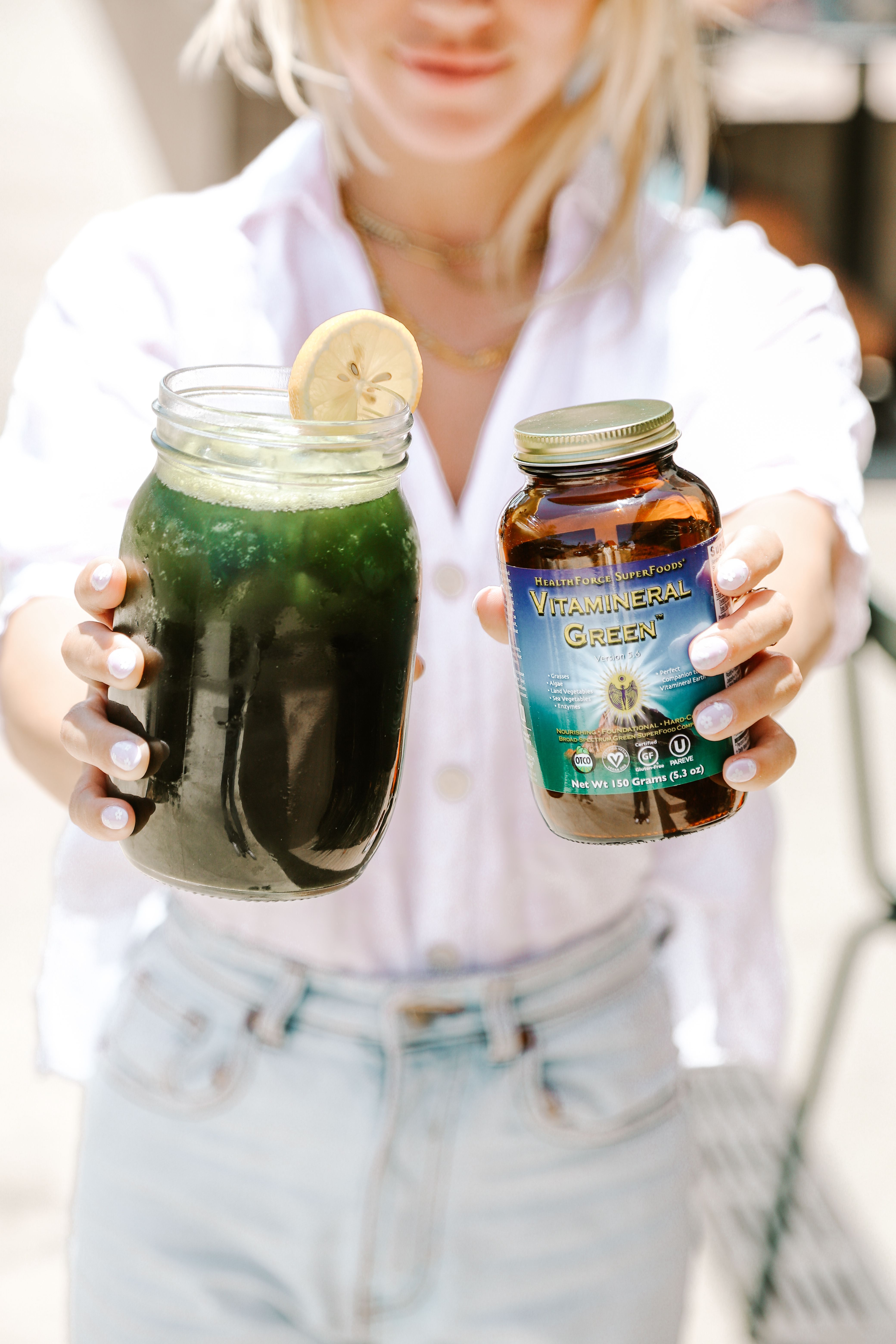Woman holding green drink with vitamin bottle