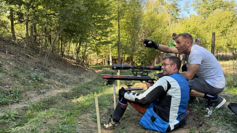 Takmičar na stajalištu dok mu drugi pokazuje metu