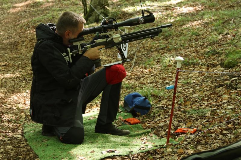 Takmičar u sedećem položaju na prostirci gađa metu nizbrdo