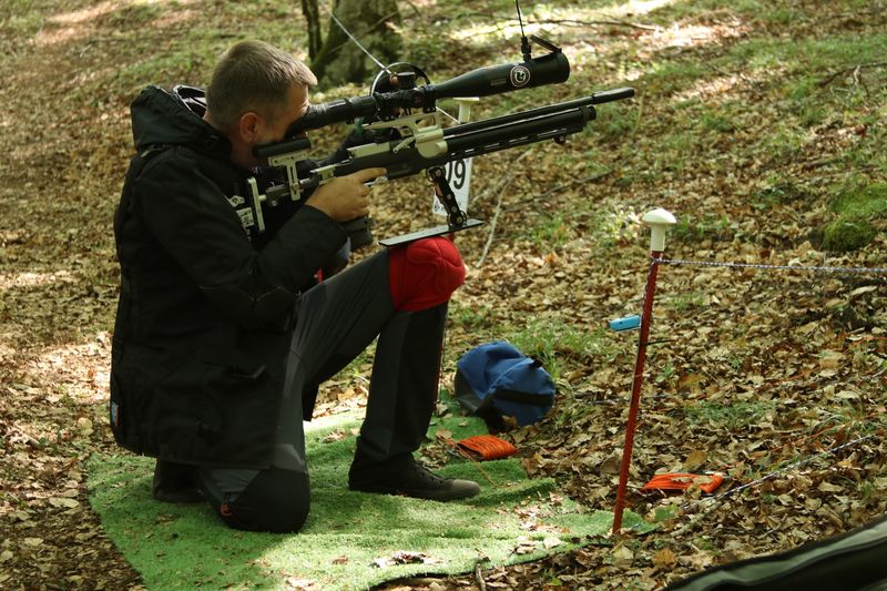 Takmičar u sedećem položaju na prostirci gađa metu nizbrdo