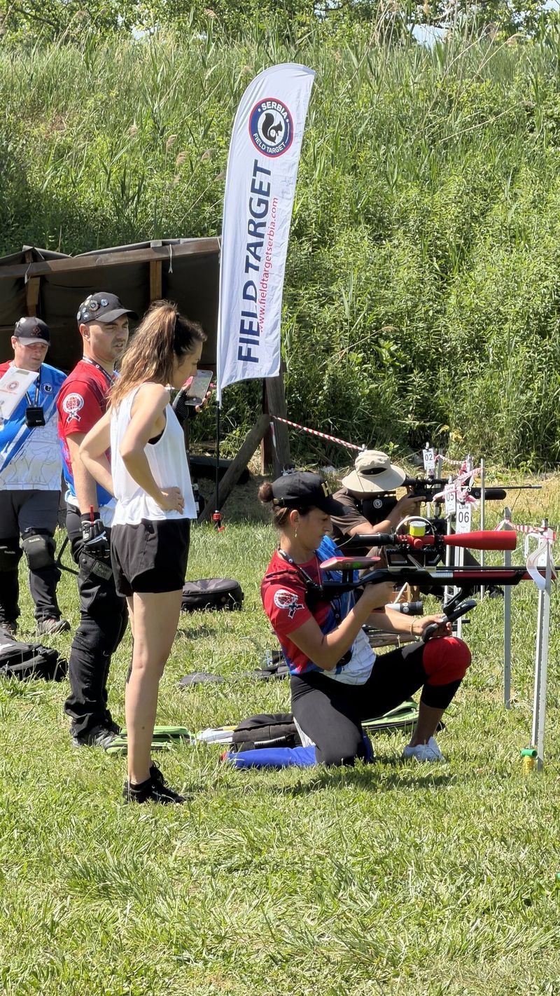 Takmičar gađa iz klečećeg položaja pored Field Target zastave, ostali prate