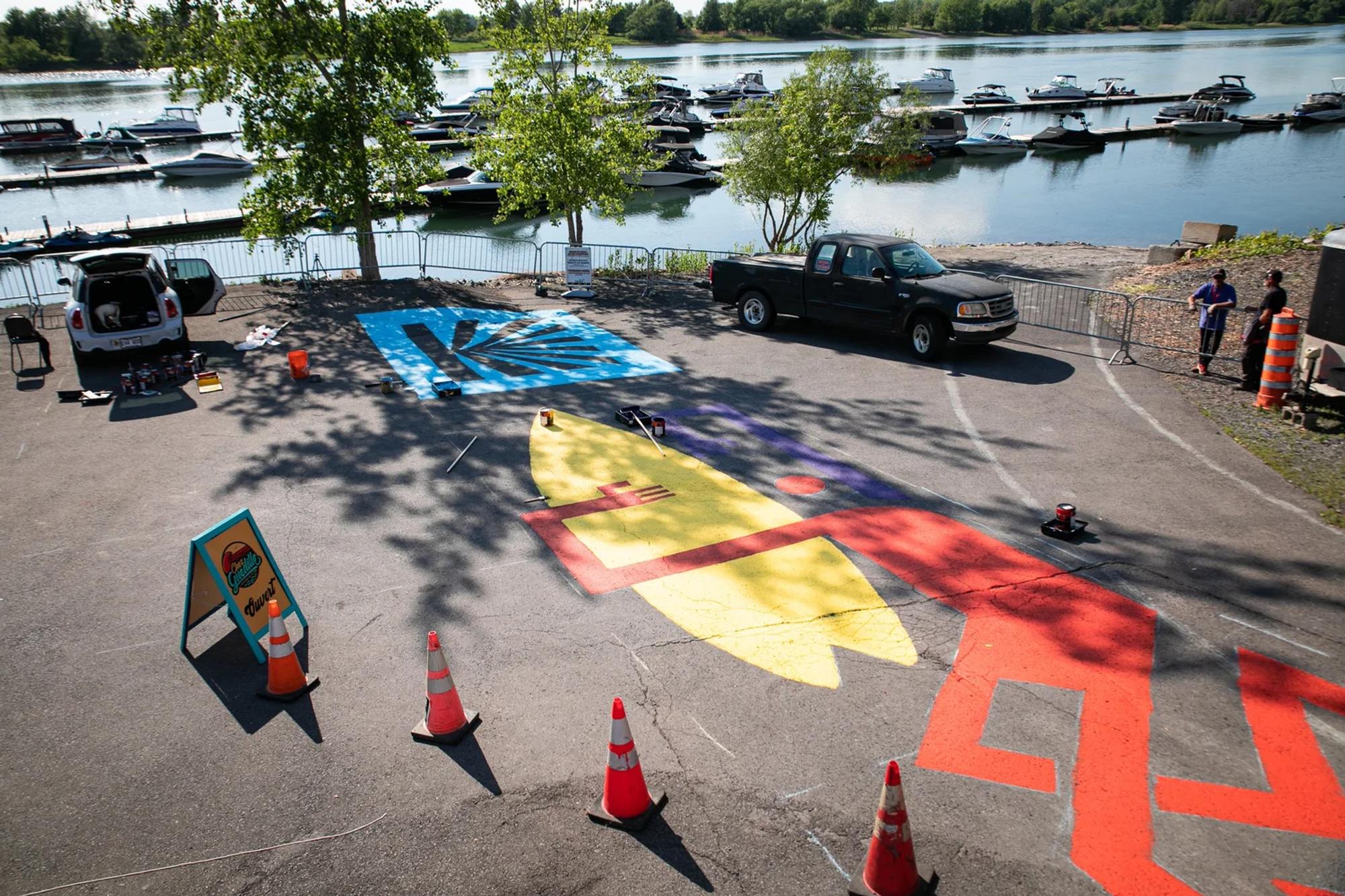 The Romeo's Gin ground mural at the Boucherville marina — pickup truck parked on the painted surface
