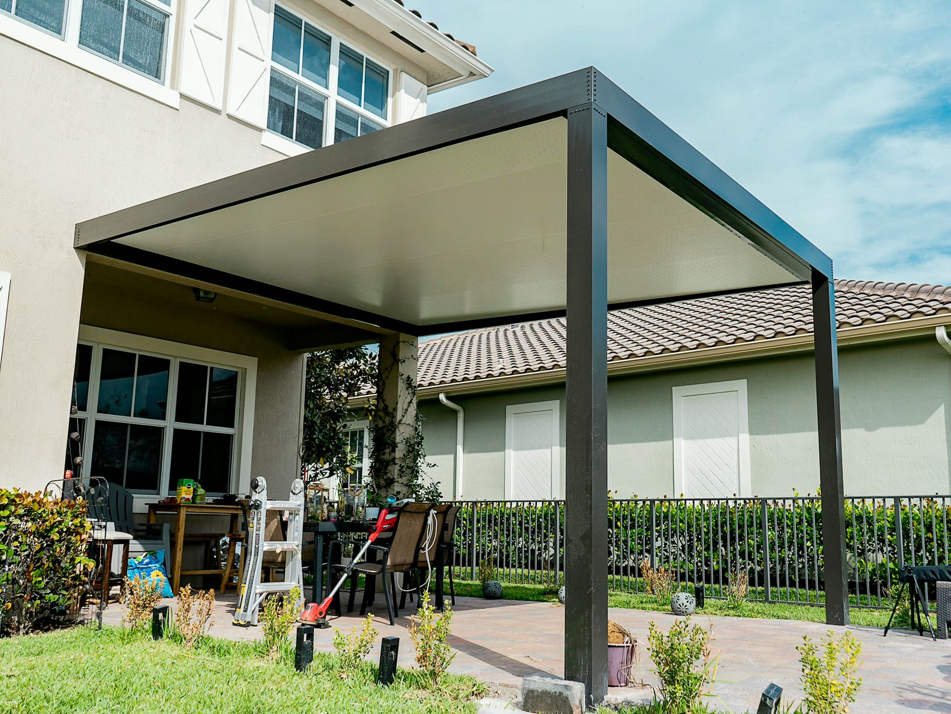 Dark gray aluminum solid-roof patio cover under-ceiling view with recessed LED lighting, pool fence visible beyond, South Florida suburban home — AB Aluminum & Screens