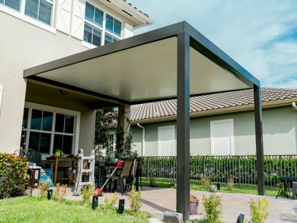 Dark gray aluminum solid-roof patio cover under-ceiling view with recessed LED lighting, pool fence visible beyond, South Florida suburban home — AB Aluminum & Screens