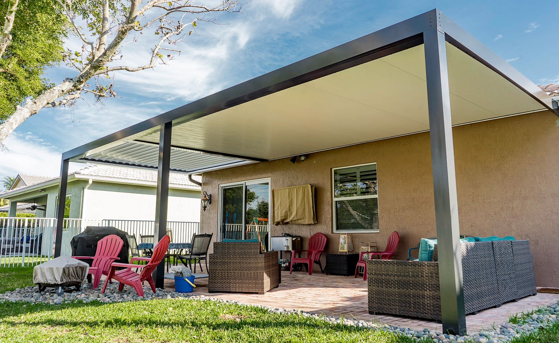White aluminum open-lattice pergola attached to Mediterranean South Florida home with arched window, terracotta tile roof, lush tropical backyard — AB Aluminum & Screens