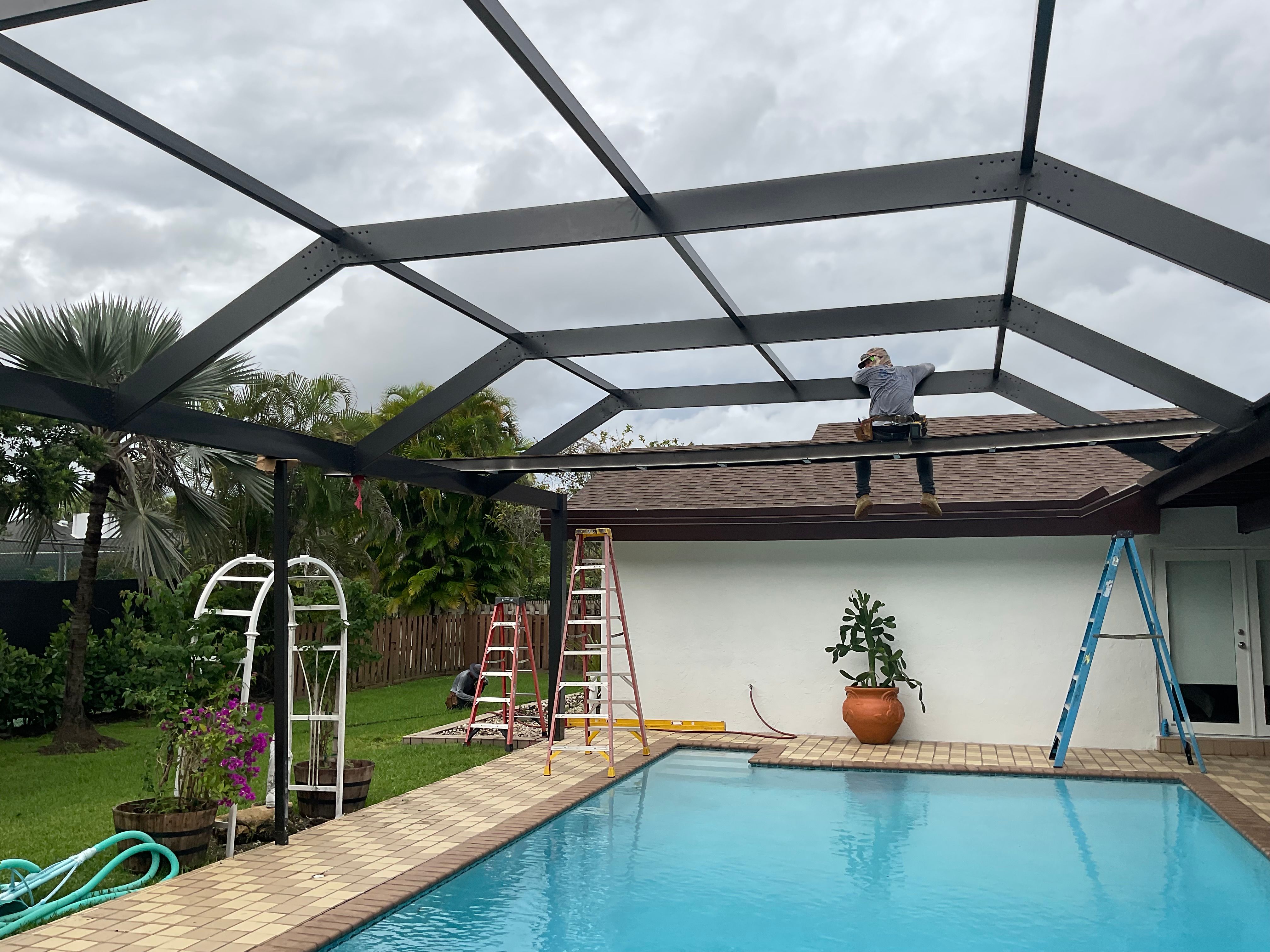 Dark bronze aluminum pool screen enclosure interior with gable roof, screened pool area with stamped concrete deck, South Florida — AB Aluminum & Screens
