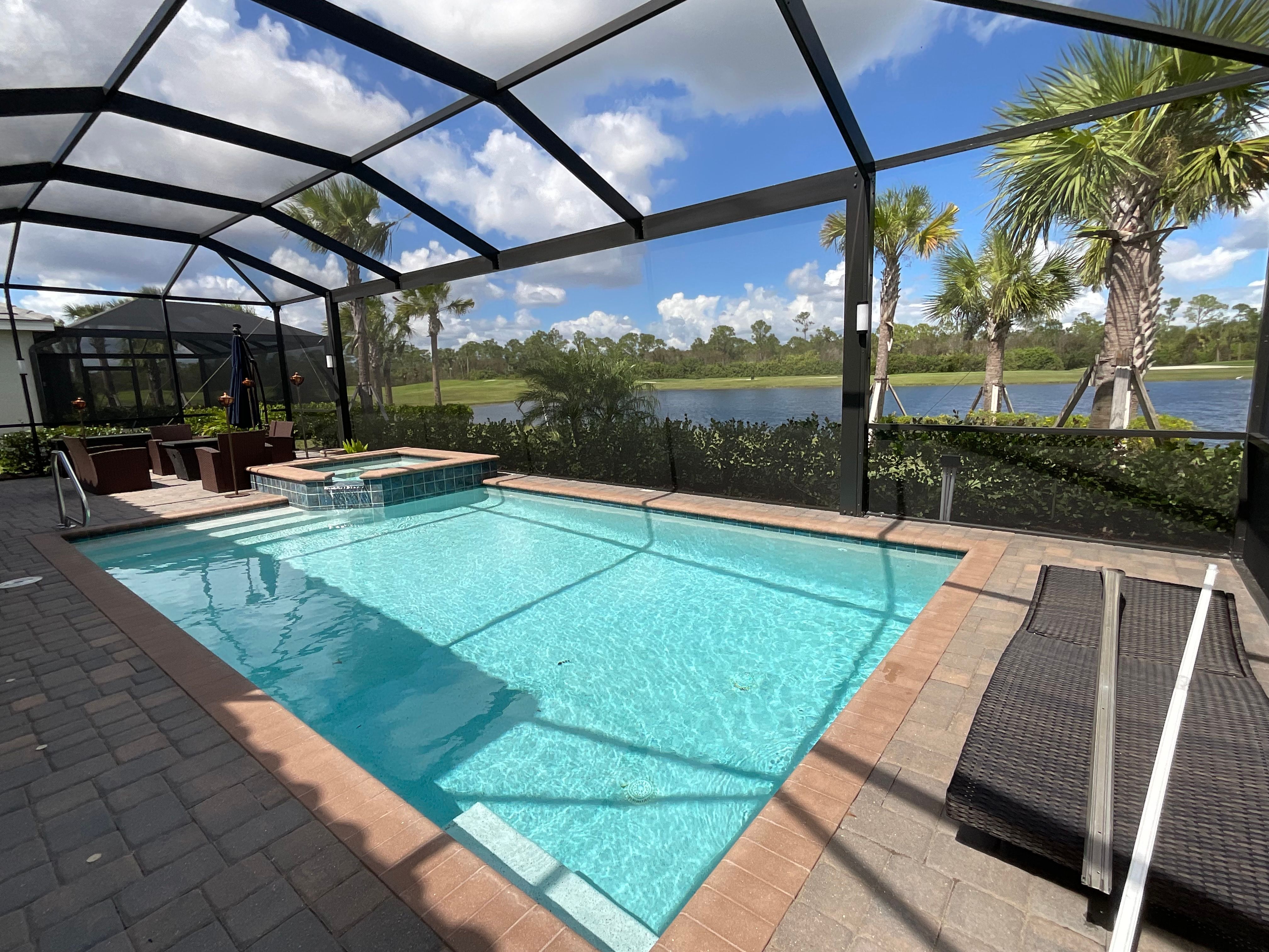 Dark bronze aluminum pool screen enclosure, rectangular pool with raised spa, travertine paver deck and open lake view, South Florida — AB Aluminum & Screens