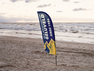 Een donkerblauwe beachwing in het zand met in de achtergond de zee.