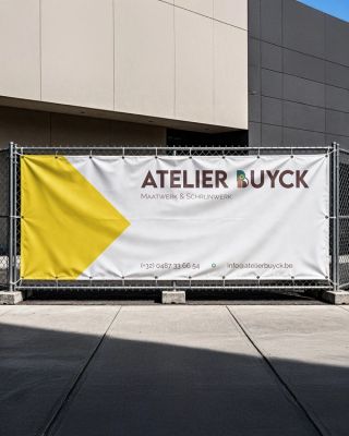 Witte werfbanner met aan de linkerkant een gele driehoek die naar rechts wijst. Aan de rechterkant van de banner staat het volledige logo: de naam Atelier buyck met de b vervangen door het logo symbool, onderaan de rechterkant staat de informatie: telefoon en email