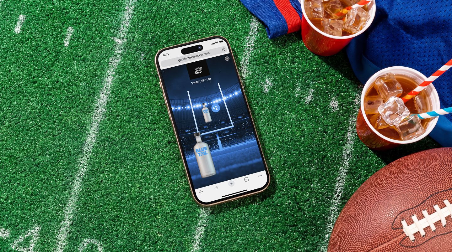 A smartphone displaying a Blue Tail ad sits on a football field beside a football, red party cups, and a blue jersey.
