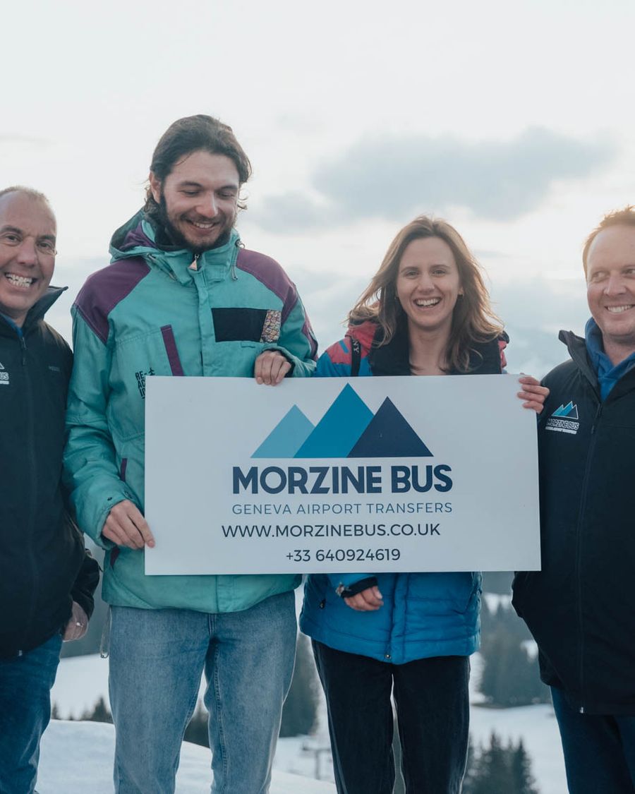 The Morzine Bus team holding a Morzine Bus sign in the snow