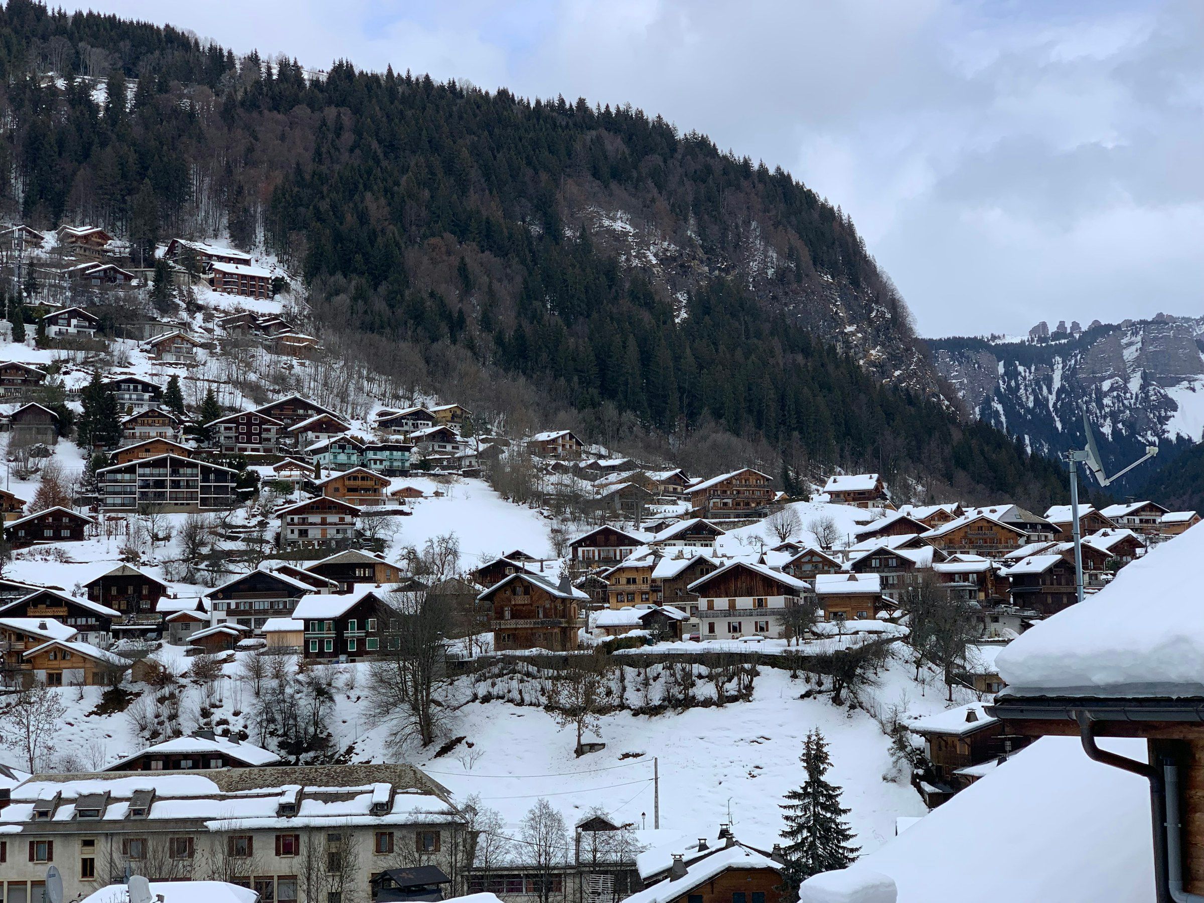 Morzine's chalets under snow, with the valley and forested mountains behind