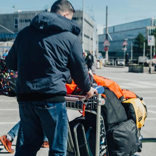 Morzine Bus driver pushing a luggage trolley with ski bags at Geneva Airport