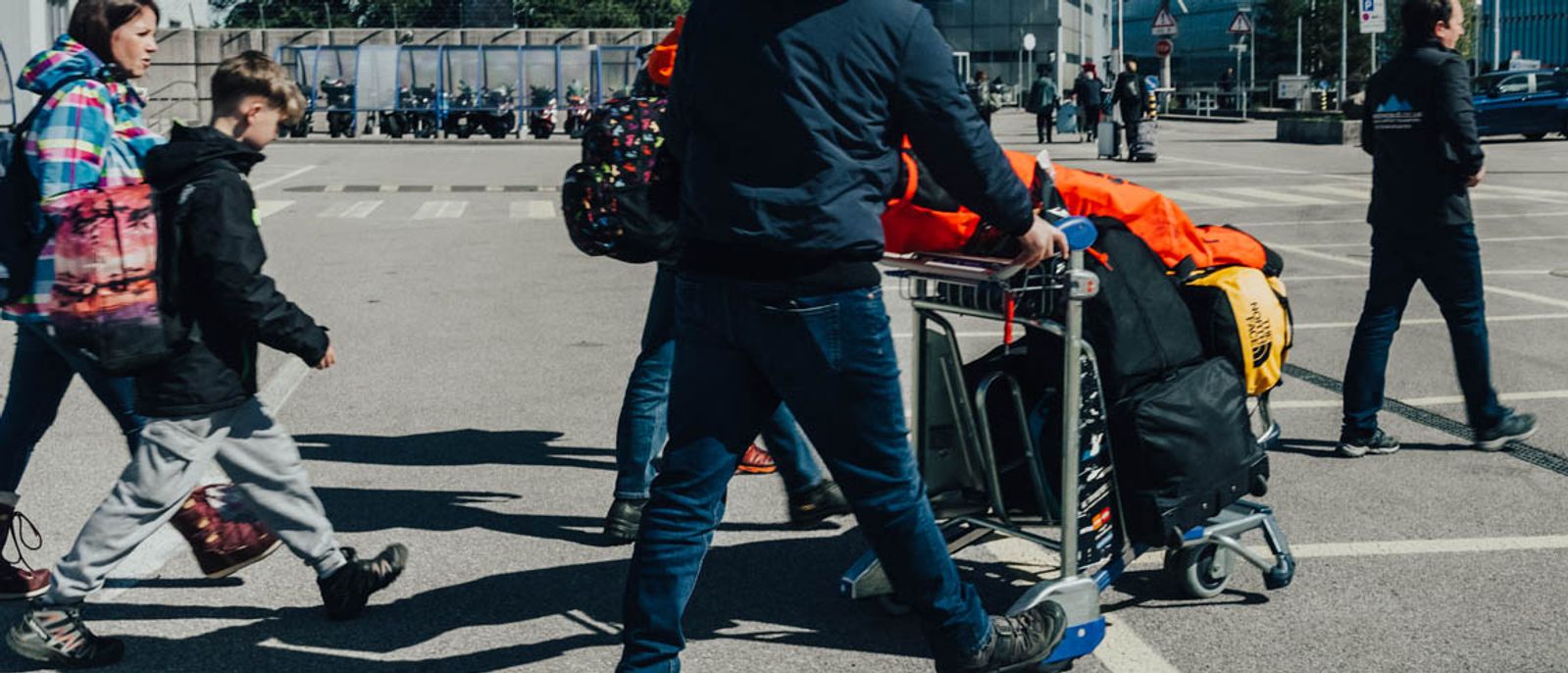 A family with ski bags walking to their transfer at Geneva Airport