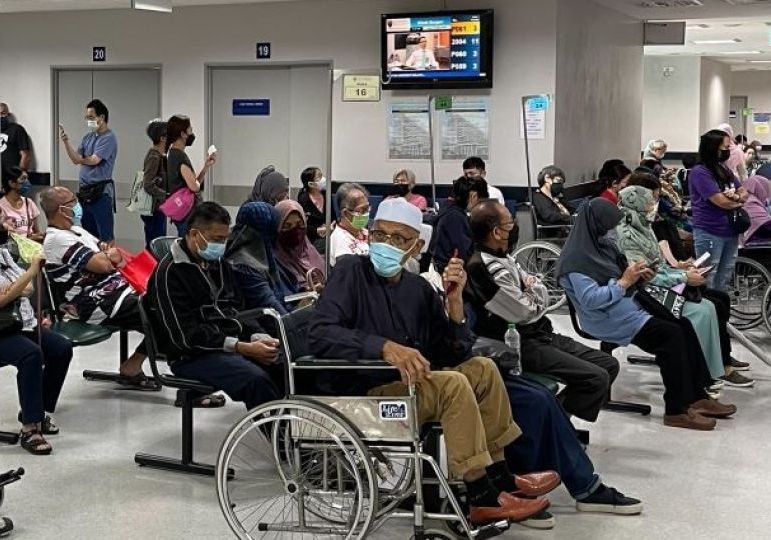 A crowded hospital waiting room with masked people, including some in wheelchairs.