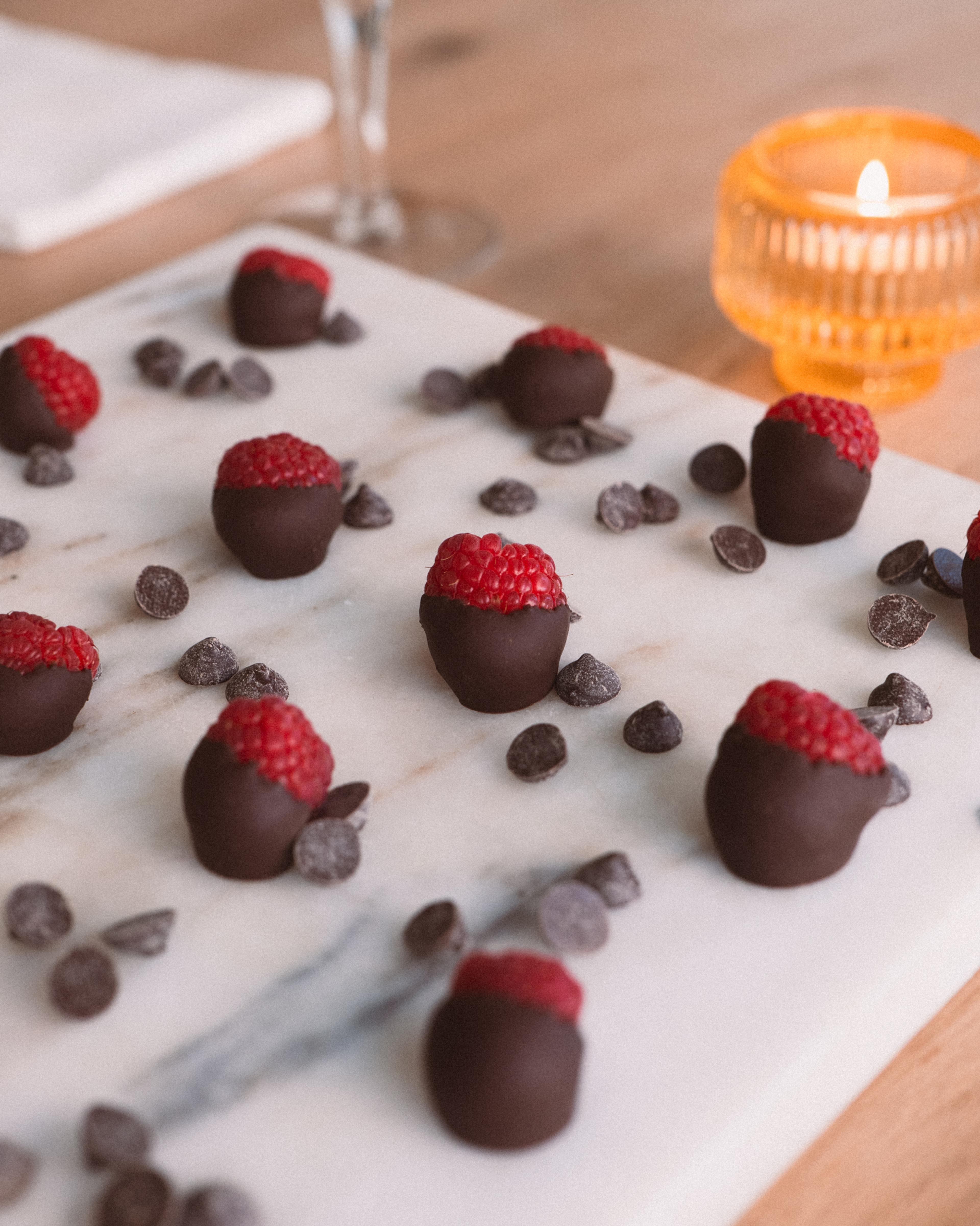 chocolate covered raspberries near a candle for valentines day