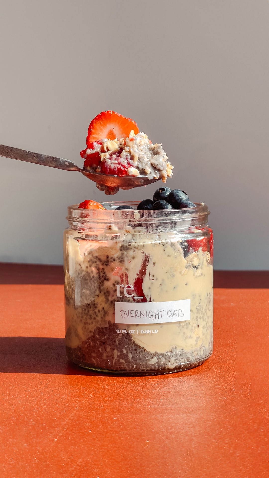 overnight chia oats with strawberries and blueberries on a red tinted tab