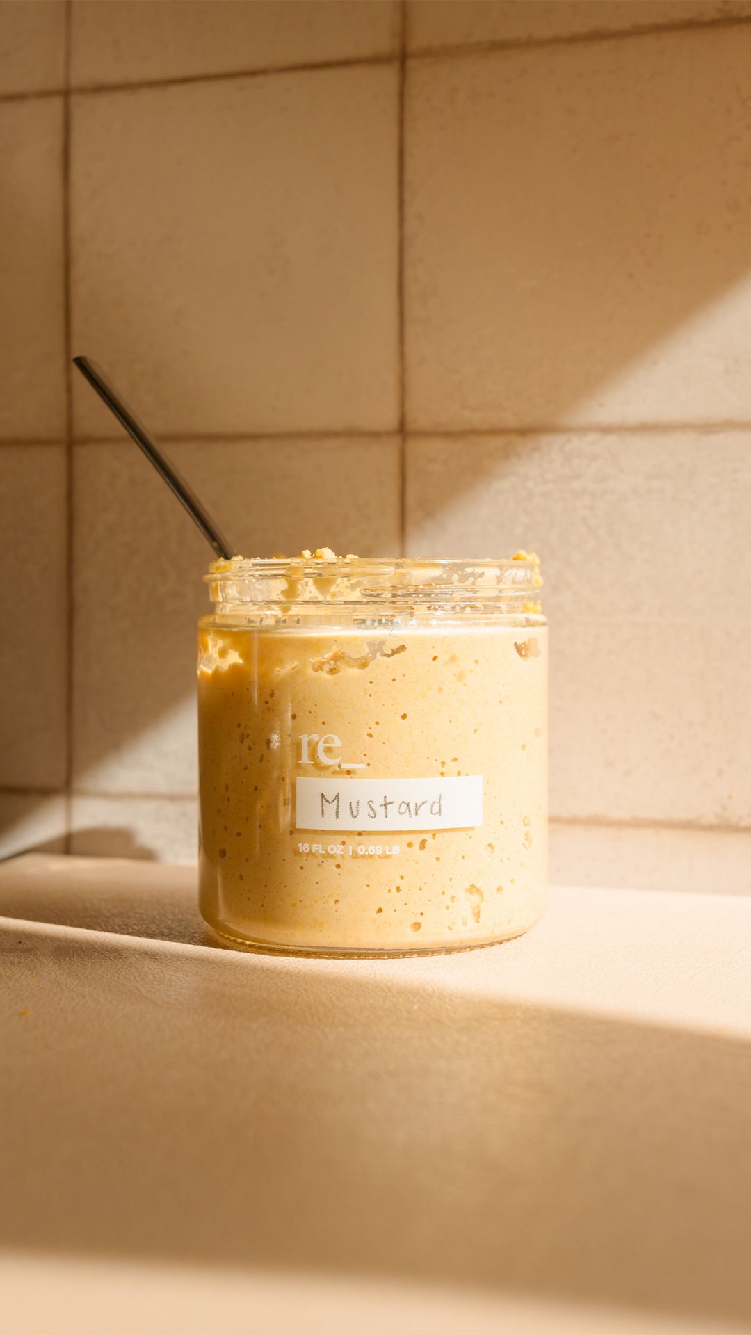 homemade mustard in a jar with a shadow cast nearby on a kitchen counter