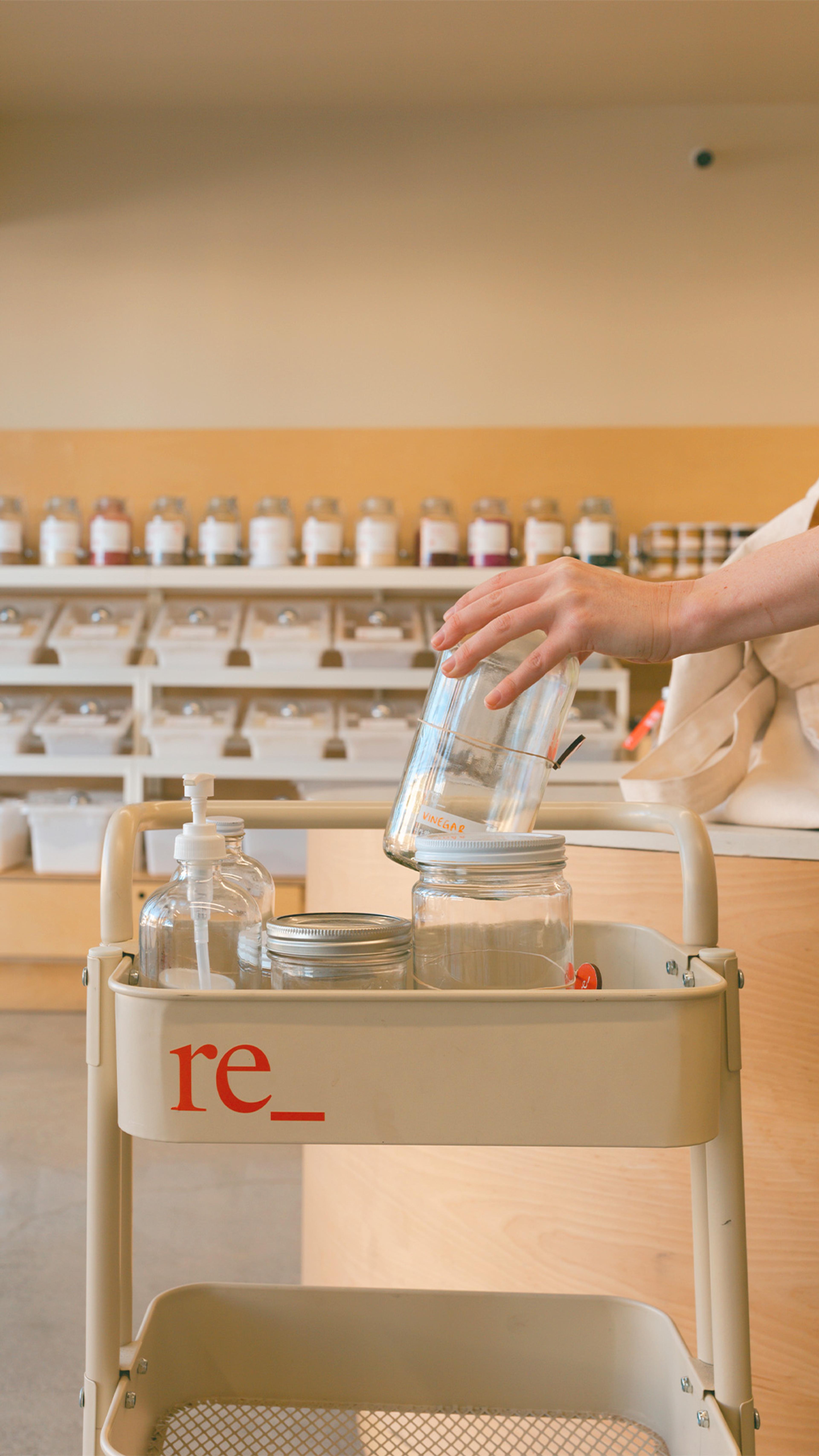 filling an empty shopping cart with glass jars and bottles with tare weights at re_ grocery