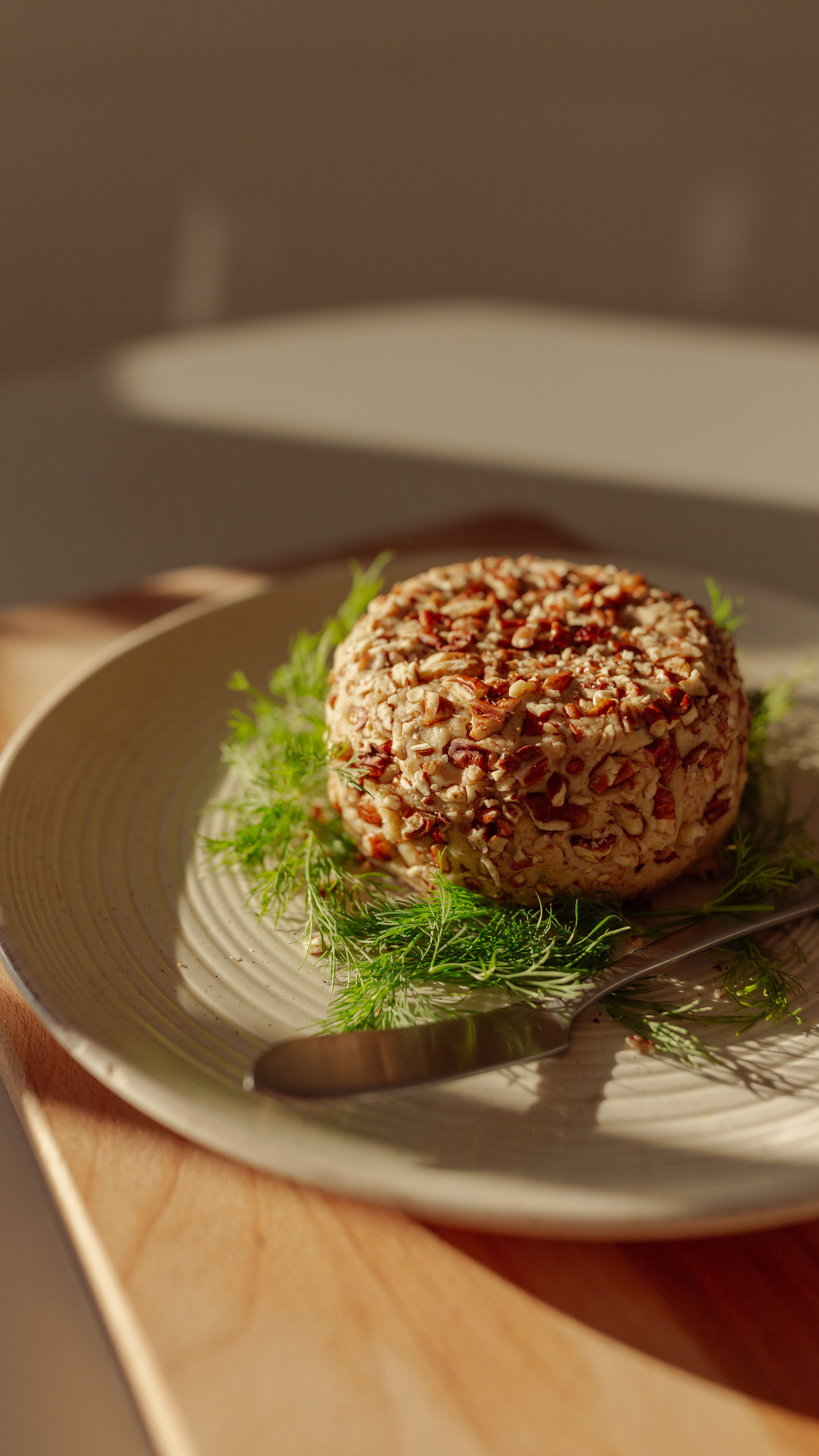vegan cashew ball with dill on a plate with shadows