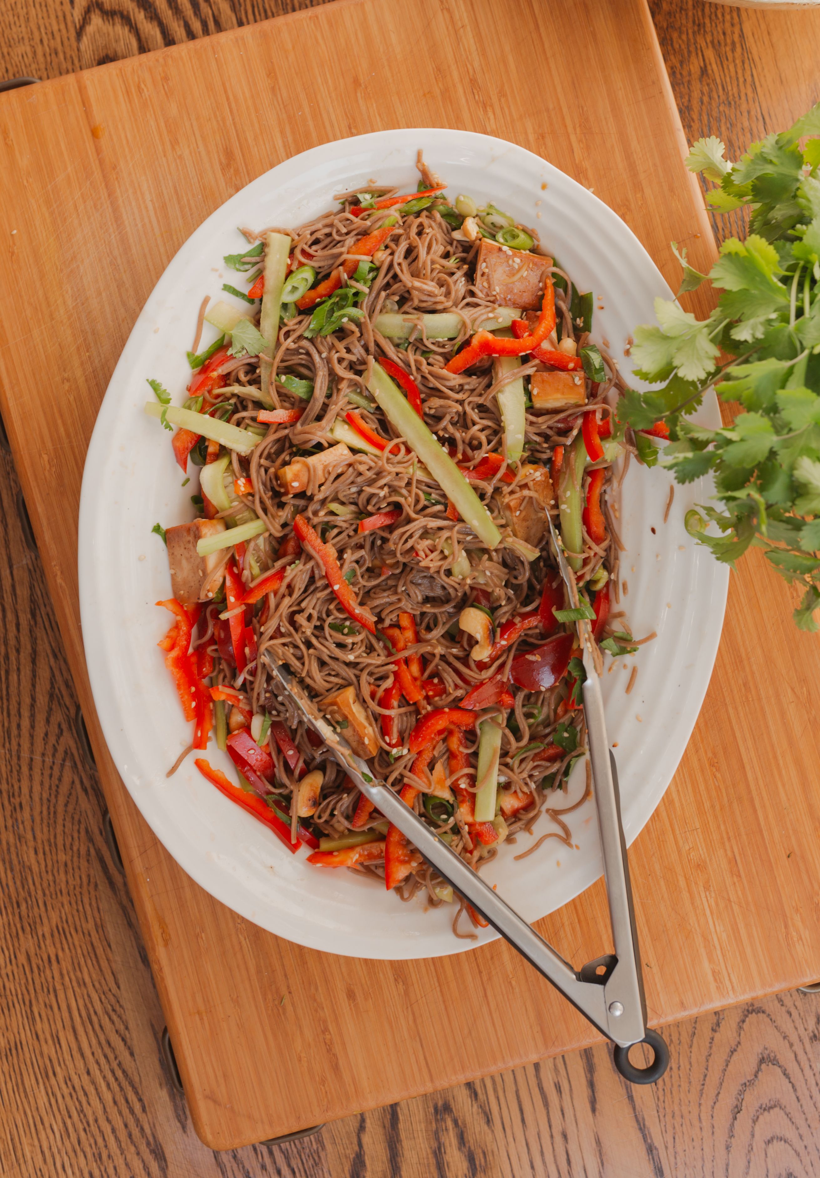 soba noodles salad on a wooden countertop near parsley and yellow onion