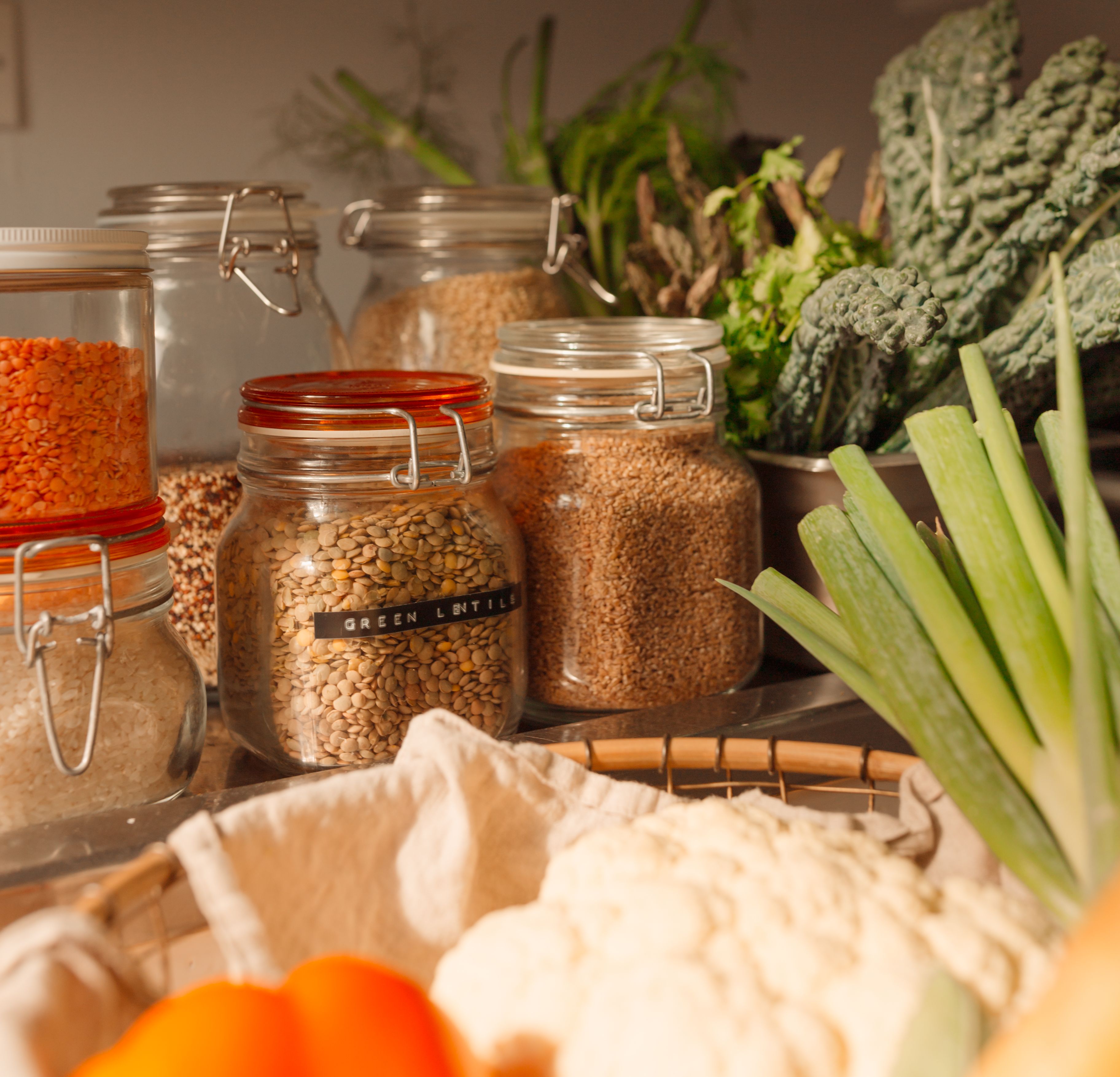 pantry staples like buckwheat, quinoa and grains on a counter with fresh produ